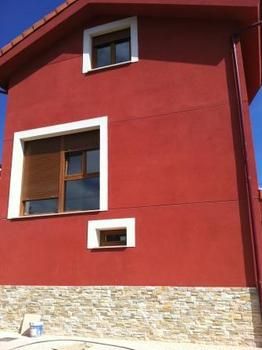 Vista lateral de casa de fachada roja con base de piedra
