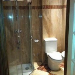 Interior de baño con inodoro y mampara de vidrio